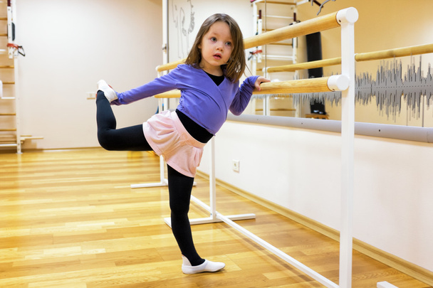 Kind, ein Mädchen engagiert sich im Ballett, Turnen, Yoga in der Turnhalle - Foto, Bild