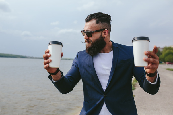 well-dressed man carries coffee - Foto, afbeelding