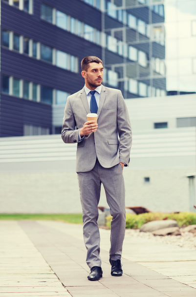 young serious businessman with paper cup outdoors - Foto, Bild