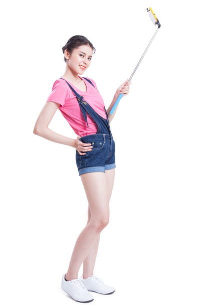 Young woman taking picture with smartphone selfie stick - Foto, Bild