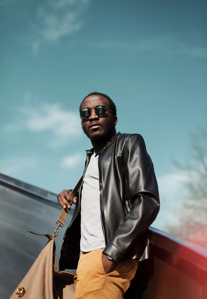 Fashion elegant young african man wearing a black leather jacket - 写真・画像