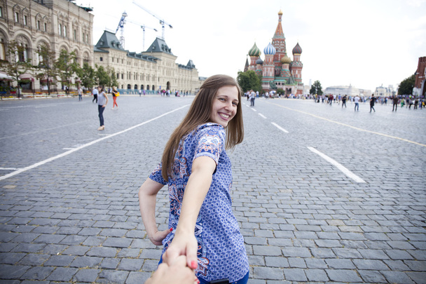 Jovem menina feliz puxa a mão caras na Praça Vermelha em Moscou
 - Foto, Imagem
