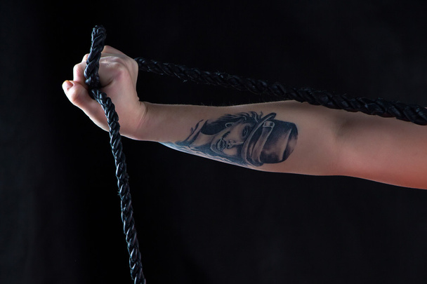 Photo womans hand with whip and tattoo - Photo, Image