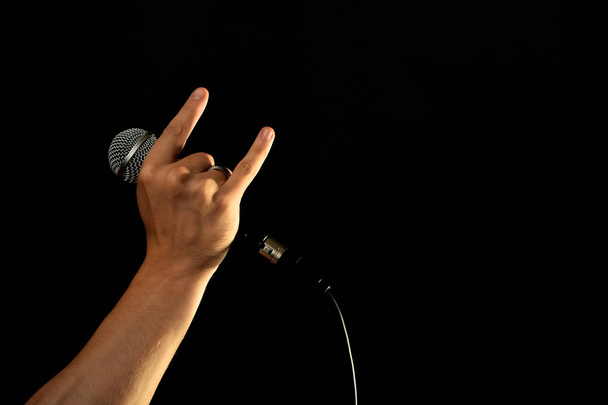 Ręka z mikrofonem i diabeł rogi na czarnym tle - Zdjęcie, obraz
