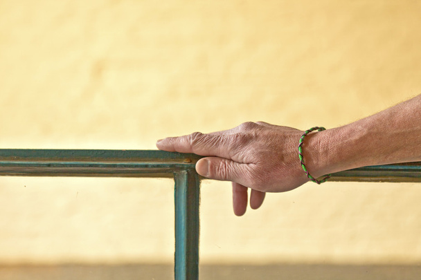 χέρι με βραχιόλι κλίνει σχετικά με ένα πλαίσιο παραθύρου - Φωτογραφία, εικόνα