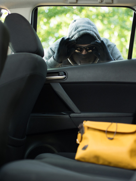 Transportation crime concept .Thief stealing bag from the car - Foto, imagen