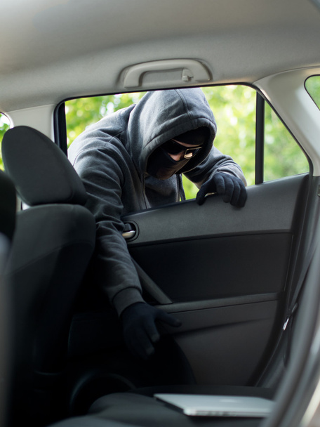 Car theft - a laptop being stolen through the window of an unoccupied car. - Photo, image