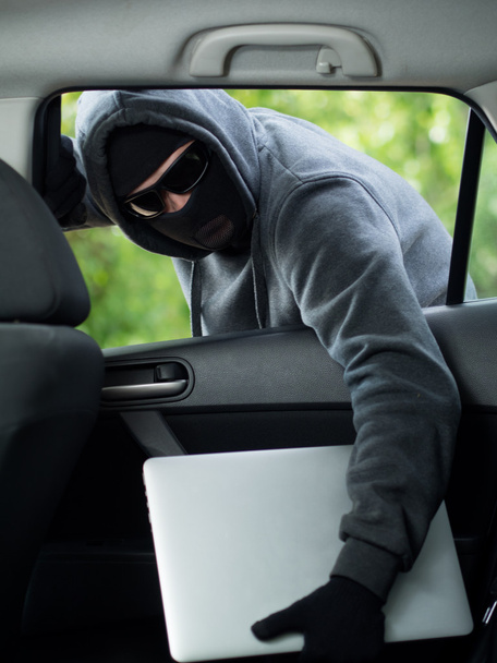 Car theft - a laptop being stolen through the window of an unoccupied car. - Foto, afbeelding