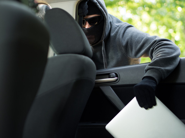 Car theft - a laptop being stolen through the window of an unoccupied car. - Photo, image