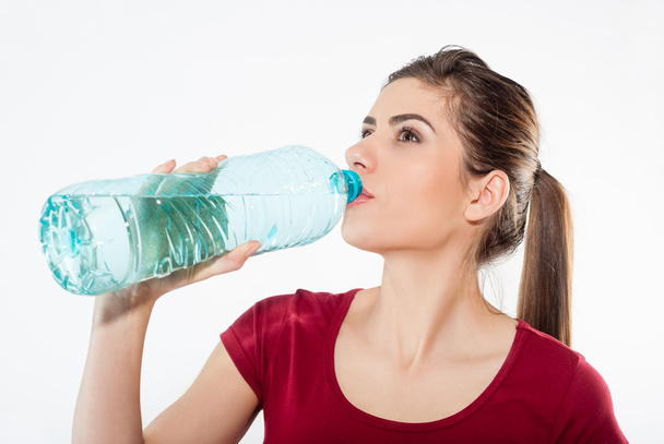 schöne Nahaufnahme Porträt einer jungen Frau, die Wasser aus der Flasche trinkt. - Foto, Bild