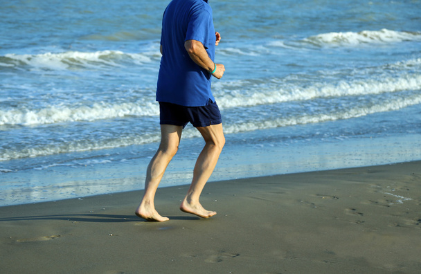 Reife Athletin läuft am Meeresstrand, um fit zu bleiben - Foto, Bild