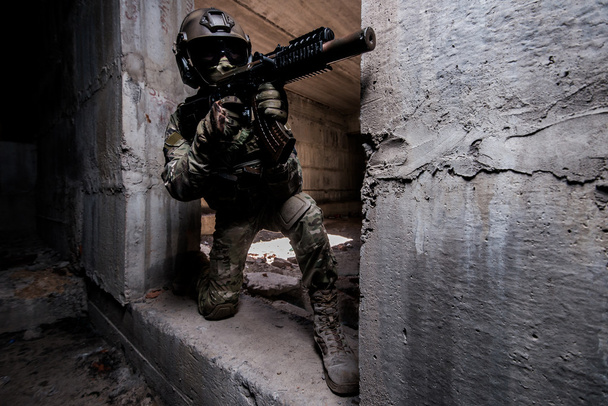 Armed ranger in in mask and helmet hiding in a building - Фото, изображение