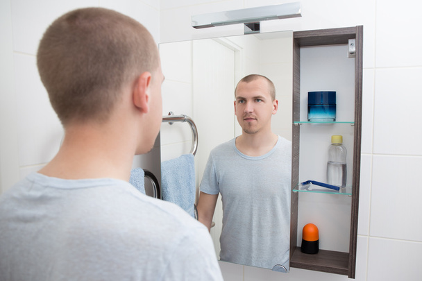 Hombre mirando el espejo en el baño
 - Foto, Imagen