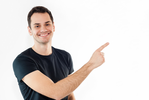 Hombre joven feliz en camiseta mostrando o señalando espacio de copia vacío
 - Foto, imagen
