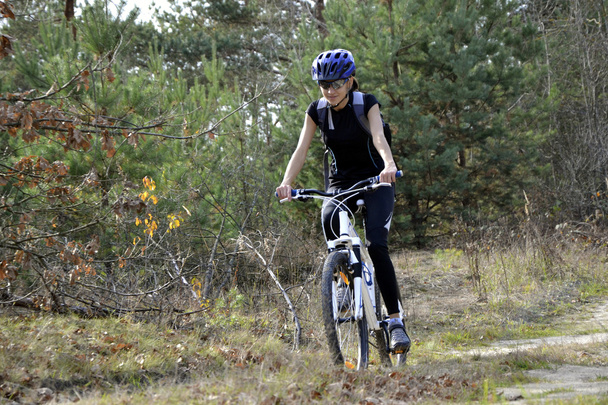 Uma menina monta uma bicicleta em uma estrada da floresta, outono
 - Foto, Imagem