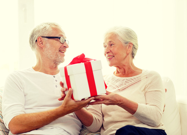happy senior couple with gift box at home - Foto, afbeelding