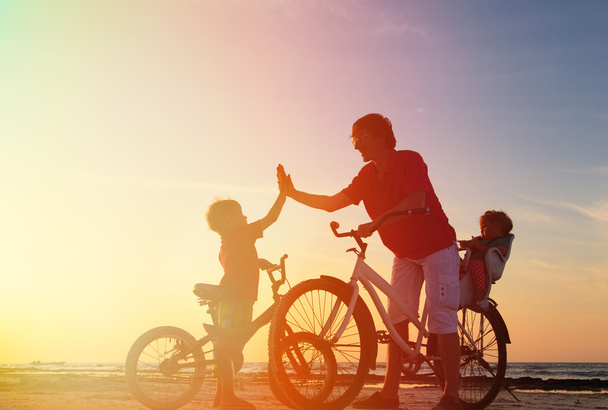 père avec enfants faisant du vélo au coucher du soleil
 - Photo, image