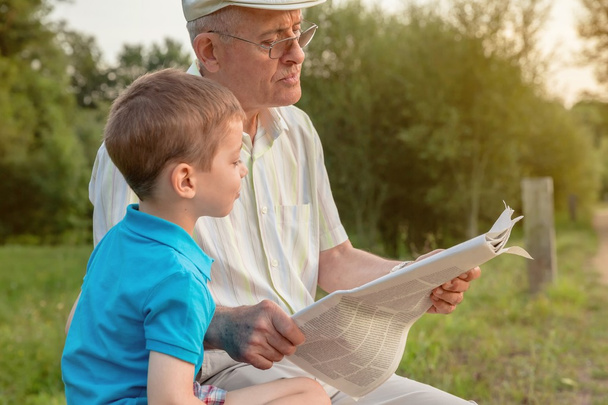 Starší muž a dítě čtení novin venku - Fotografie, Obrázek