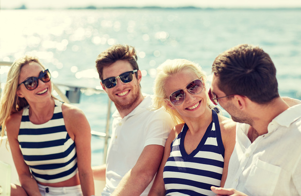 smiling friends sitting on yacht deck - Fotó, kép