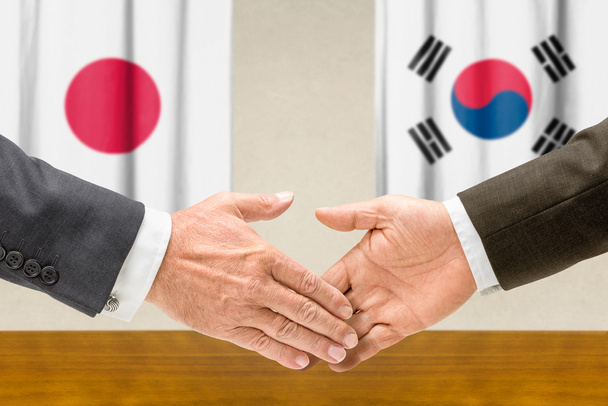 Representantes do Japão e da Coreia do Sul apertam as mãos
 - Foto, Imagem