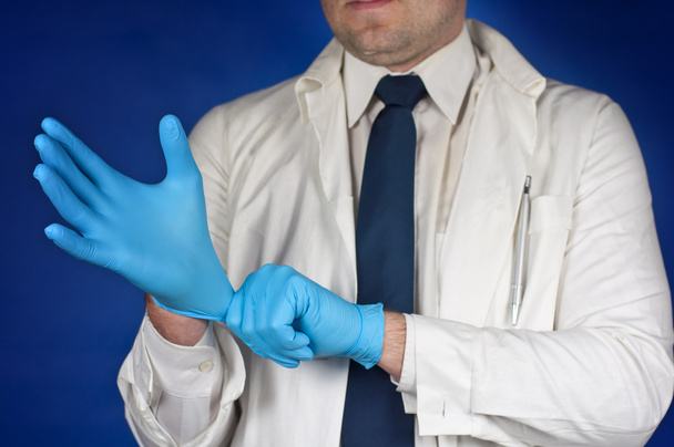 Doctor putting on protective gloves isolated on blue - Фото, зображення