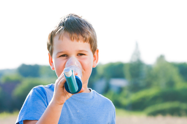 Menino usando inalador para asma na aldeia com pôr do sol de verão
 - Foto, Imagem
