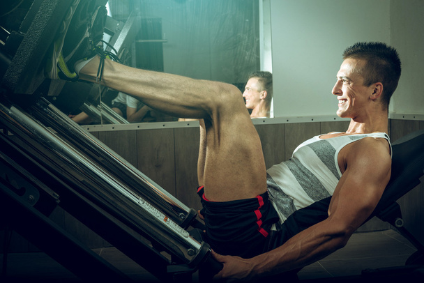 Man using leg press in gym - Fotó, kép