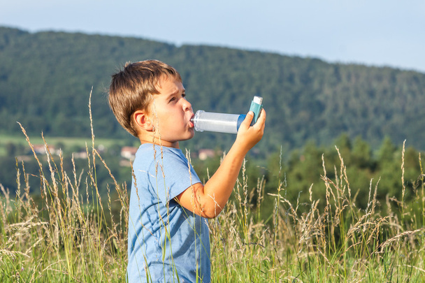 Chłopiec przy użyciu inhalatora astmy w miejscowości z letnich zachód słońca - Zdjęcie, obraz