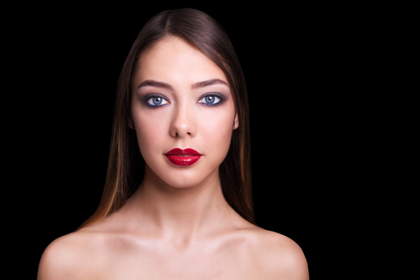 Nauwe portret van een mooi meisje met een rode lippen en rokerige ogen. Geïsoleerd op zwarte achtergrond. Kopiëren van ruimte. - Foto, afbeelding