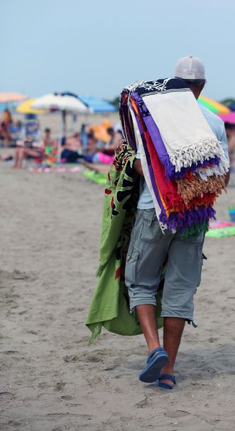 Afrikanischer Hausierer von Handtüchern und Strandtüchern am Strand - Foto, Bild