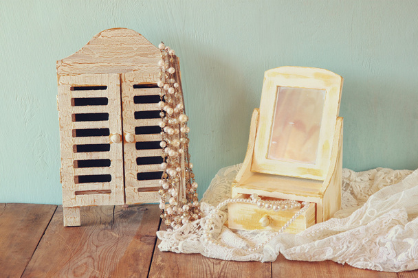 vintage pearls , antique wooden jewelry box with mirror and perfume bottle on wooden table. filtered image - Foto, Bild
