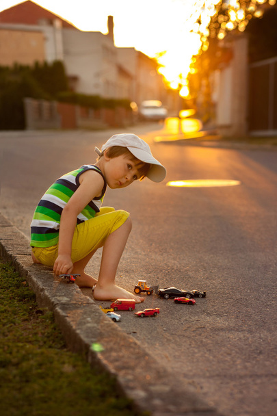 Cute little boy, playing with little toy cars on the street on s - Foto, imagen