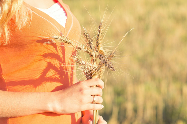 Girl with ripe ears of barley in hand - Foto, afbeelding