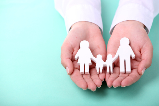 weibliche Hände halten Spielzeugfamilie auf farbigem Hintergrund - Foto, Bild
