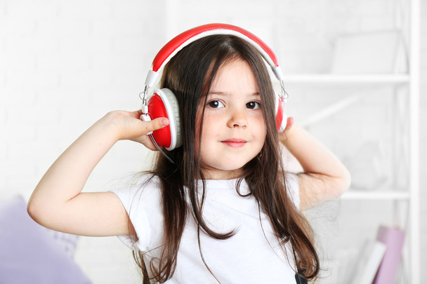 Beautiful little girl listening to music in room - Photo, Image