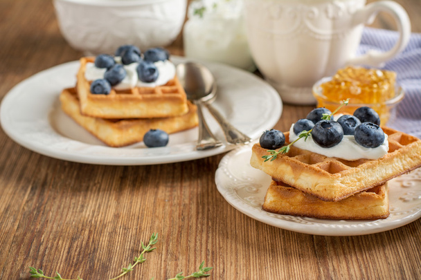 Homemade fresh crispy waffles for breakfast with blueberries and honey - 写真・画像