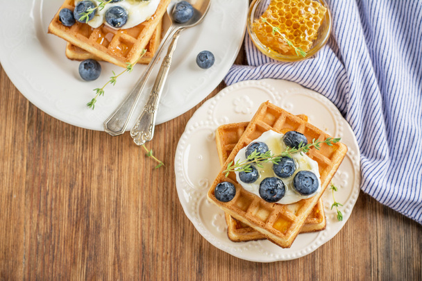 Homemade fresh crispy waffles for breakfast with blueberries and honey - Foto, afbeelding