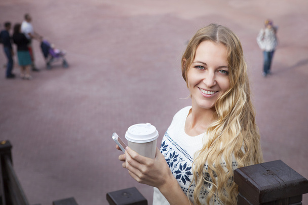 Χαμογελώντας μοντέρνο ξανθιά γυναίκα που κρατά καφέ σε εξωτερικούς χώρους - Φωτογραφία, εικόνα