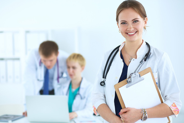 Attractive female doctor  with folder in front of medical group - Foto, Imagen