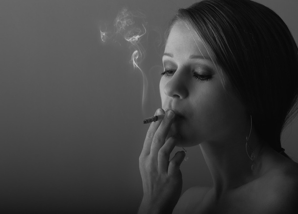 Beautiful young woman smoking a cigarette - Фото, зображення