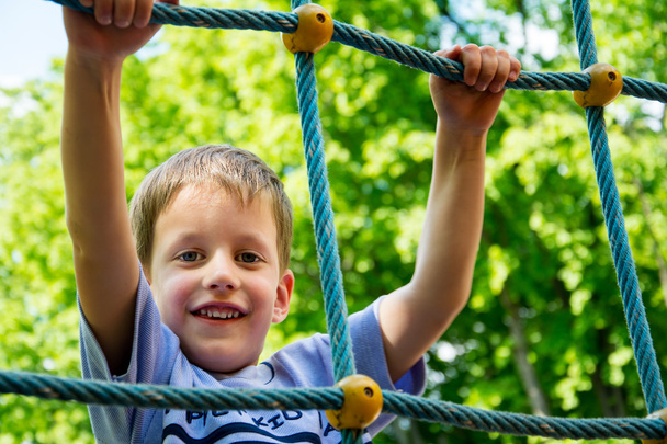 Young boy climbing rope on kid playground - Photo, image