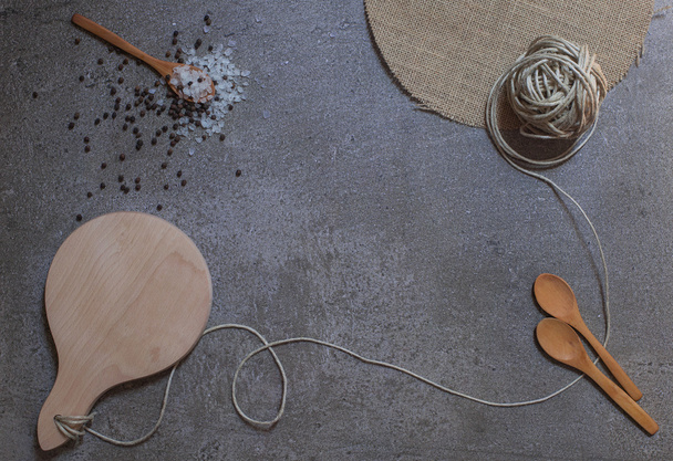 Wooden spoons, cutting board and knot on the stone background - Foto, afbeelding