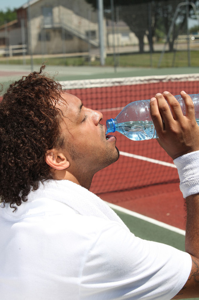 Male tennis player drinking water - Foto, afbeelding