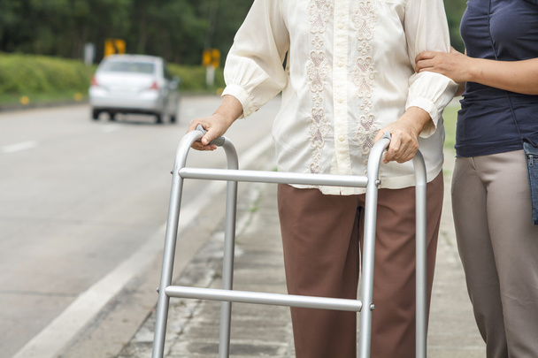 Vanhempi nainen, joka käyttää kävelijää.
 - Valokuva, kuva