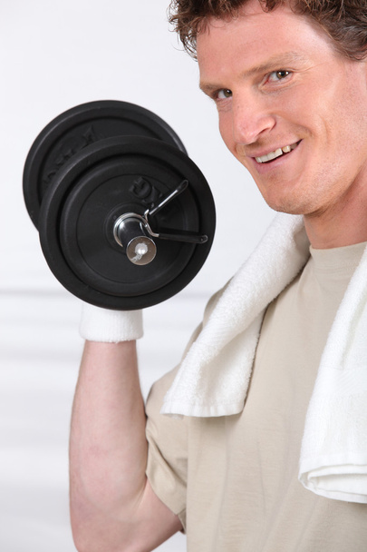Smiling man lifting barbell on white background - Foto, Imagen