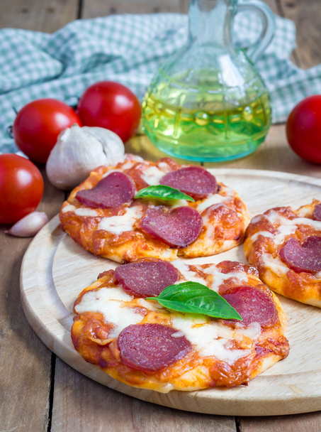 Mini pizza al salame piccante fatta in casa su una tavola di legno
 - Foto, immagini