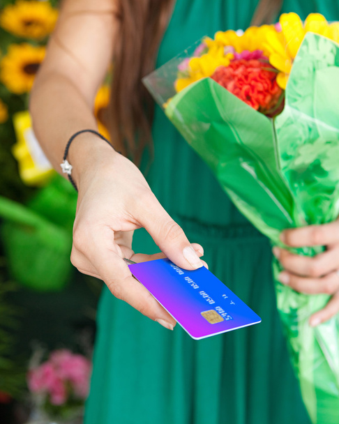 woman with a bouquet of fresh flowers and credit card - Φωτογραφία, εικόνα