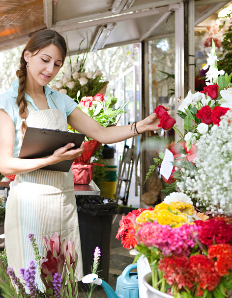 florist woman works in her store with a a clipboard - Fotó, kép