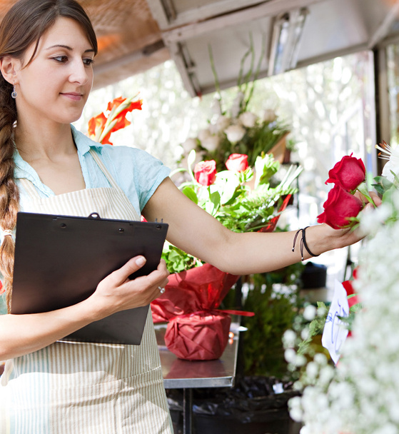 florist woman works in her store with a a clipboard - Foto, afbeelding