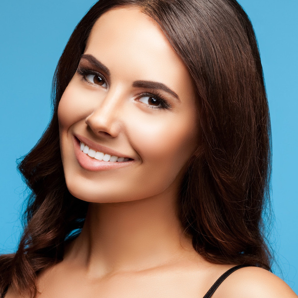 closeup of beautiful young smiling brunette woman, on blue - Foto, Imagem